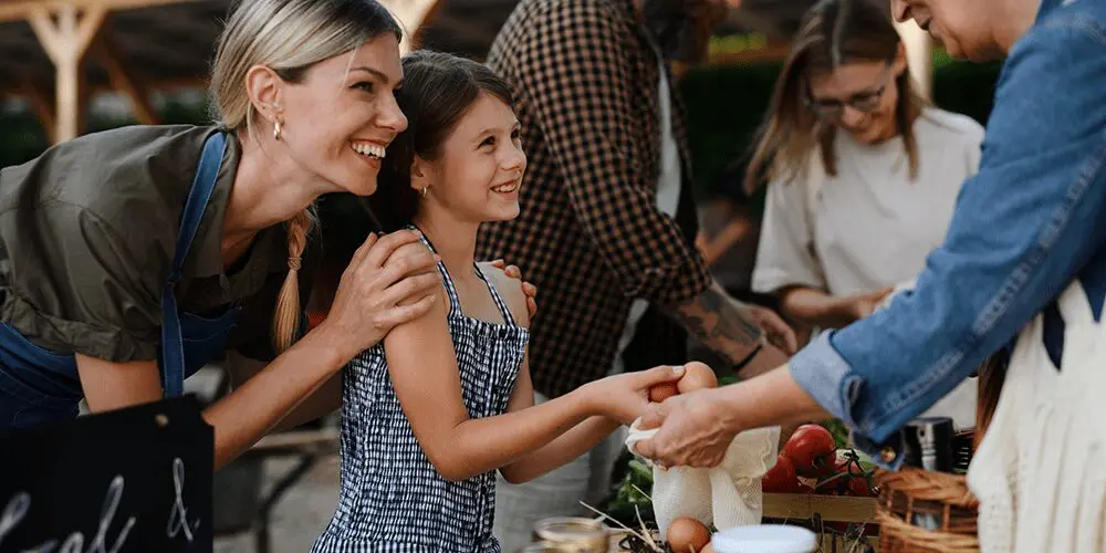 happy woman and child at a farmers market selling/buying eggs