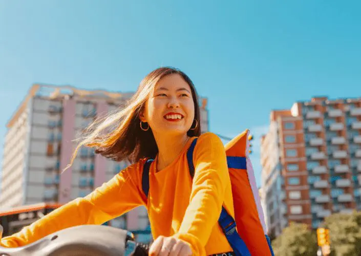 person riding a bike in the city and the sun is shining