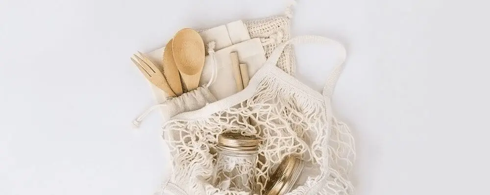 Shopping bag filled with sustainable kitchen utensils and drinkware.