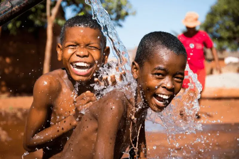 Children playing in water provided by charitable actions related to the Fill it Forward program.