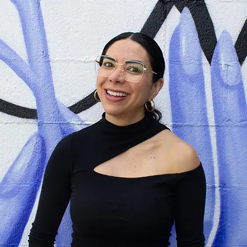 Alma standing in front of a mural