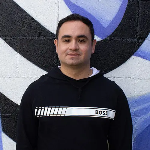 Luis standing in front of a mural
