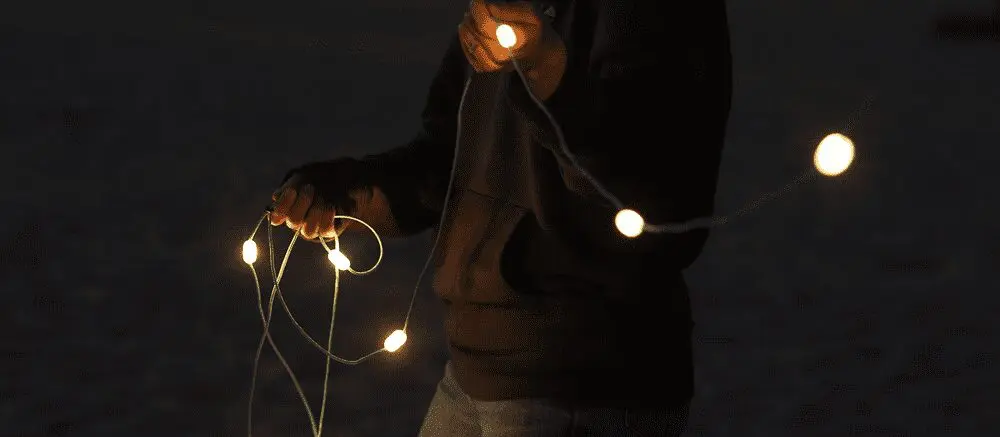 person in the dark holding solar powered string lights