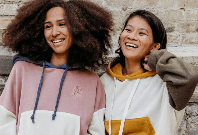 two people wearing hoodies smiling