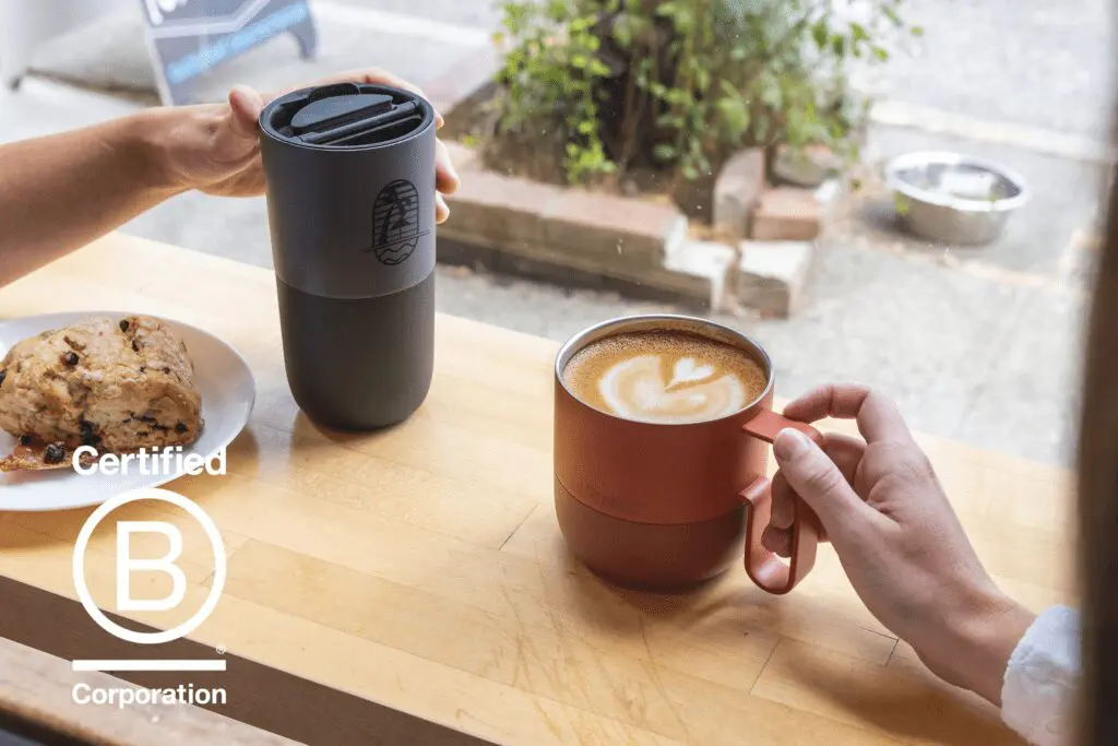 Two people having coffee at a window sill in a coffee shop, enjoying coffee in reusable klean kanteen drinkware