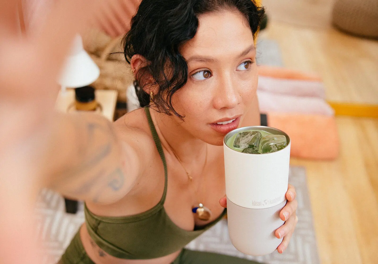 woman in a yoga outfit drinking from her reusable cup.