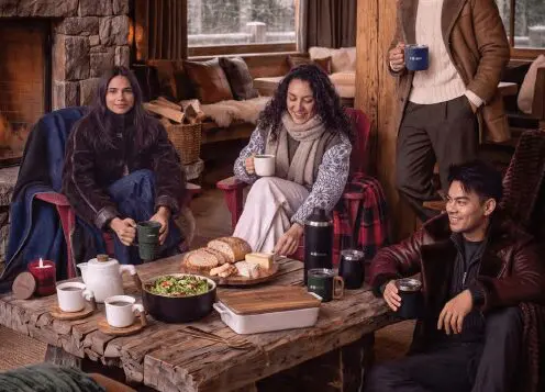Friends sitting around a cozy cabin in front of a wood coffee table full of gifting wares