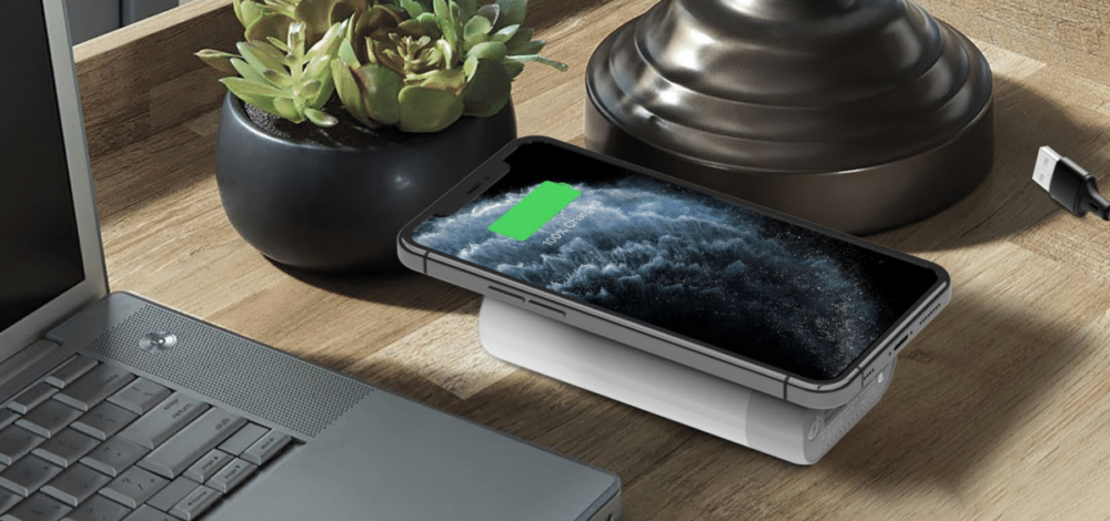 PORTABLE CHARGERS - image shows a phone on top of a qi charger on a desk.