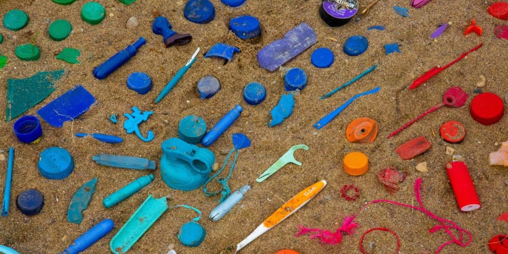 Plastic garbage items laying in the sand.