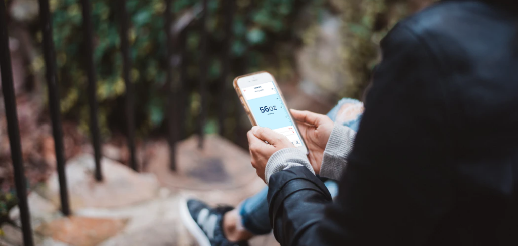 Person sitting outside looking at app on phone.