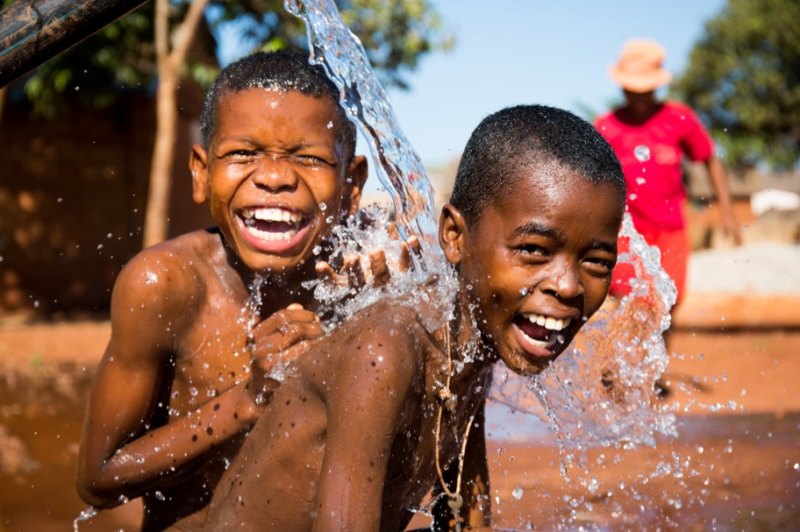 Children playing in water provided by charitable actions related to the Fill it Forward program.