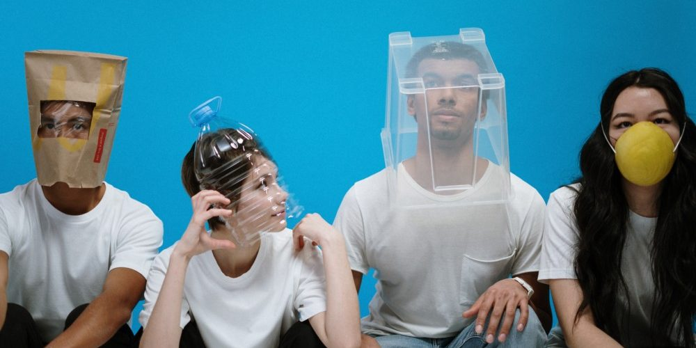 Group of people with various containers over their faces in front of a blue background.