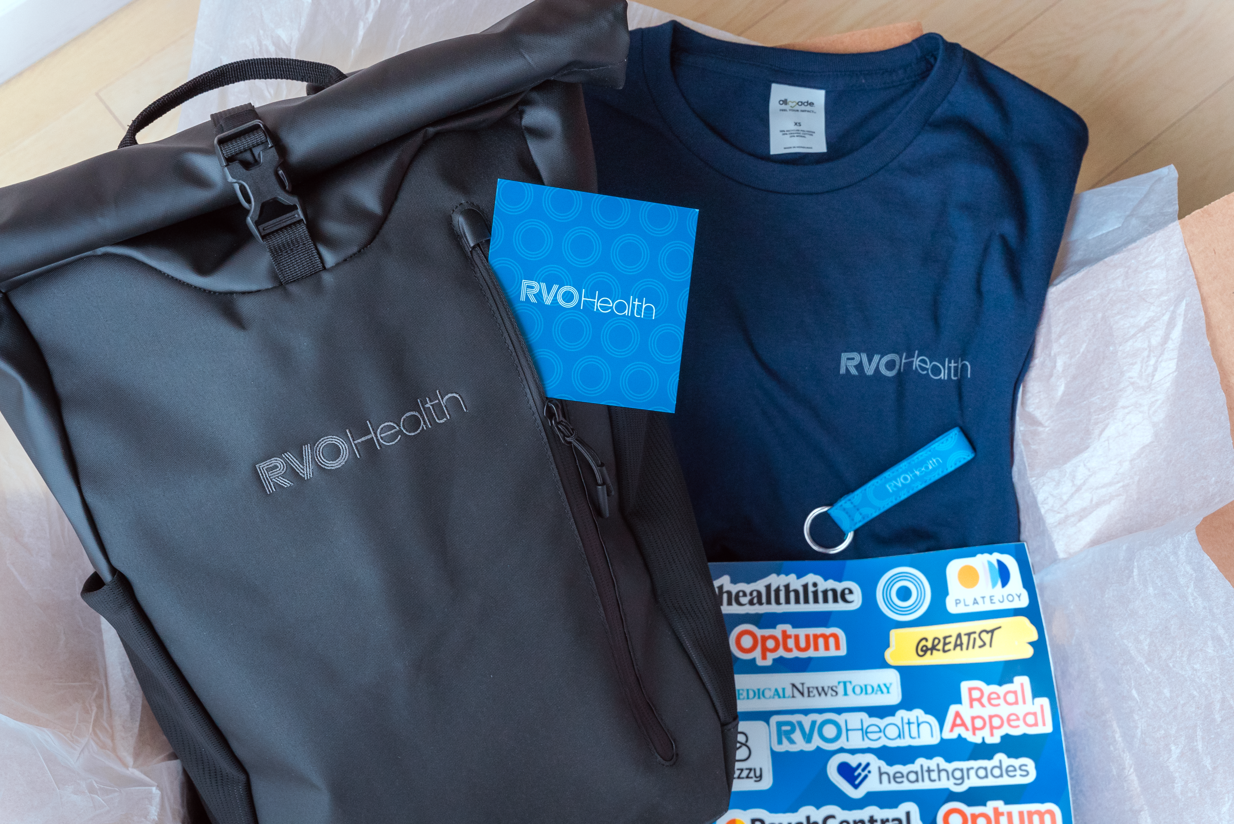 RVO HEalth Employee kit including bag, t-shirt, postcard, sticker sheet, and keychain