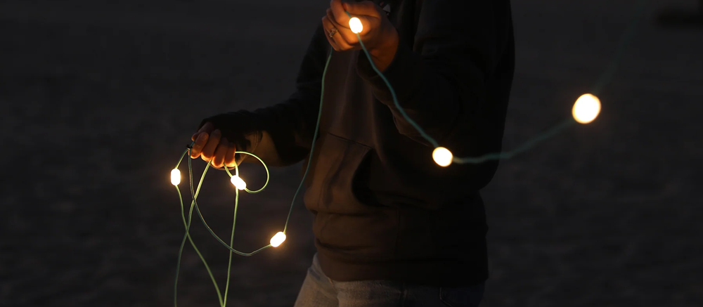 person in the dark holding solar powered string lights