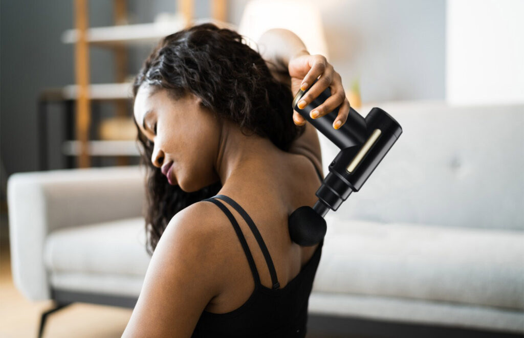 person massaging their back with a massage gun