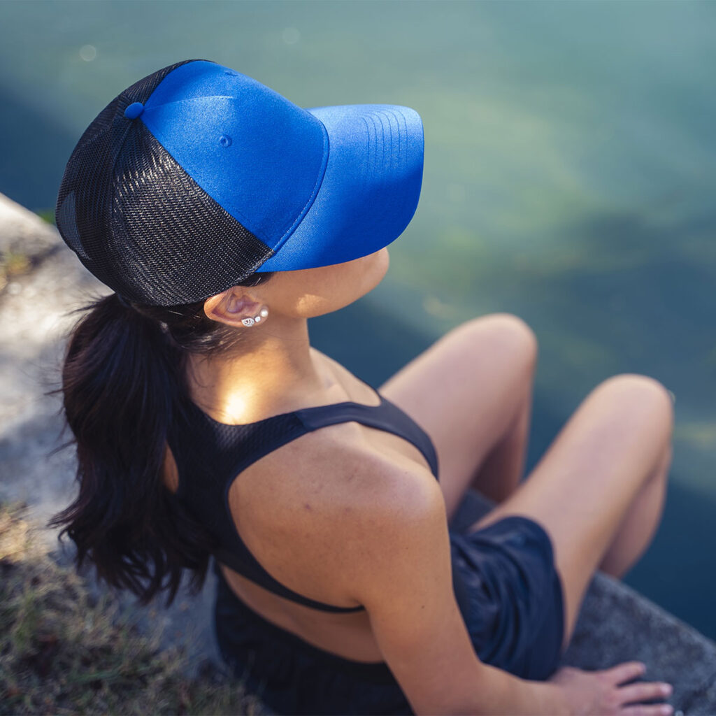 ball cap made from recycled plastics work by a women at the waters edge.