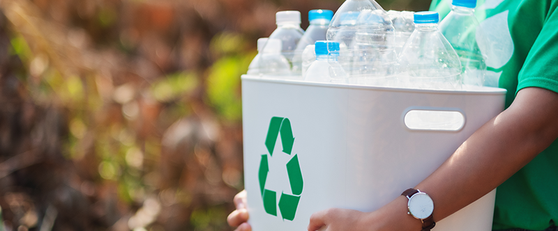 Person carrying a recycling container filled with clean empty water bottles.