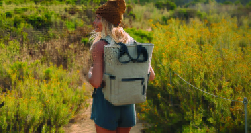 woman standing in a field wearing a backpack