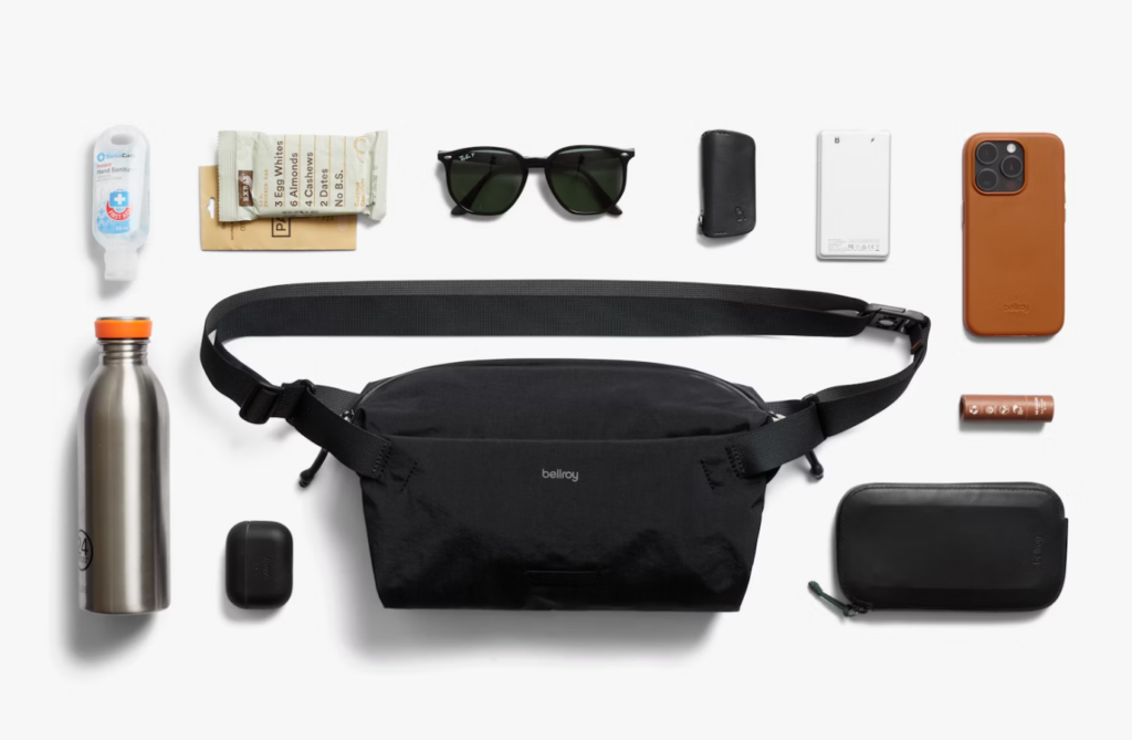 Image of a flat lay showing how many items fit inside the featured product that is a bellroy black sling bag.