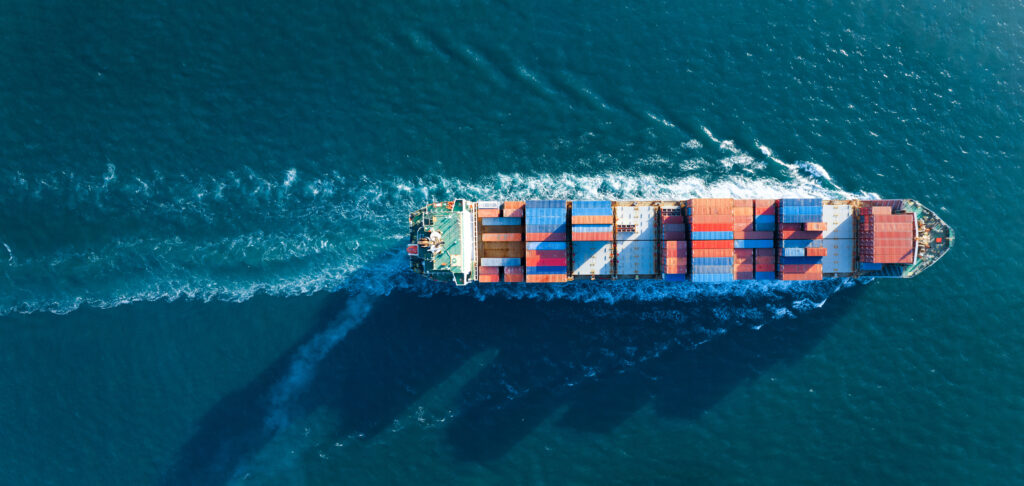 Aerial top view of cargo ship carrying container and running for export goods from cargo yard port to custom ocean concept technology transportation , customs clearance.