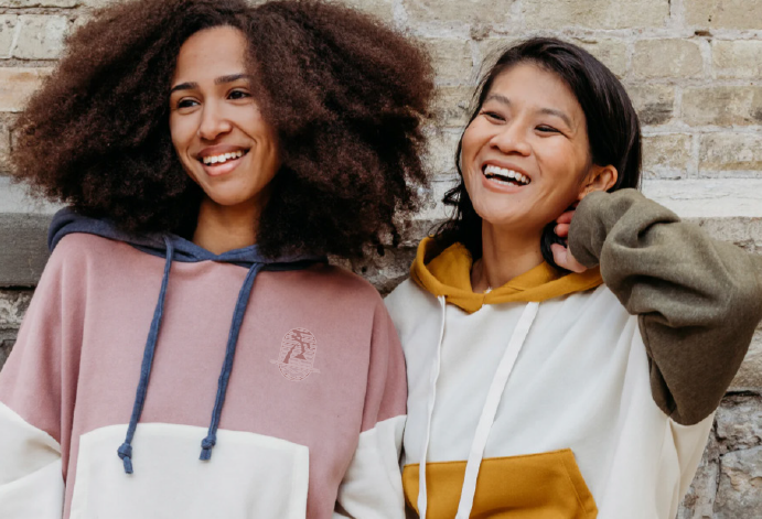 two people wearing hoodies smiling