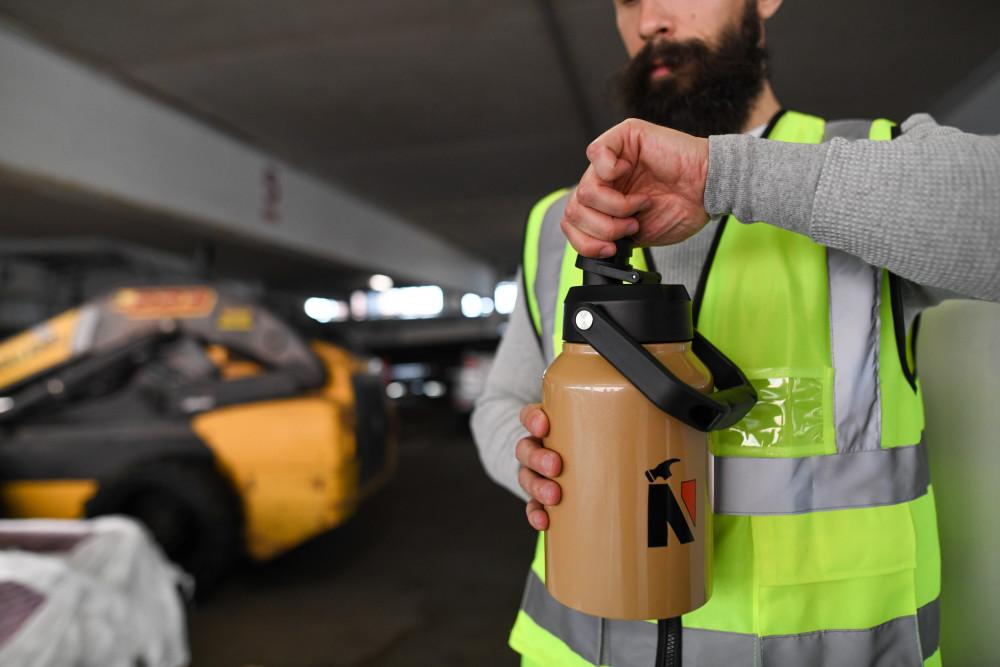 man drinking from large branded water bottle