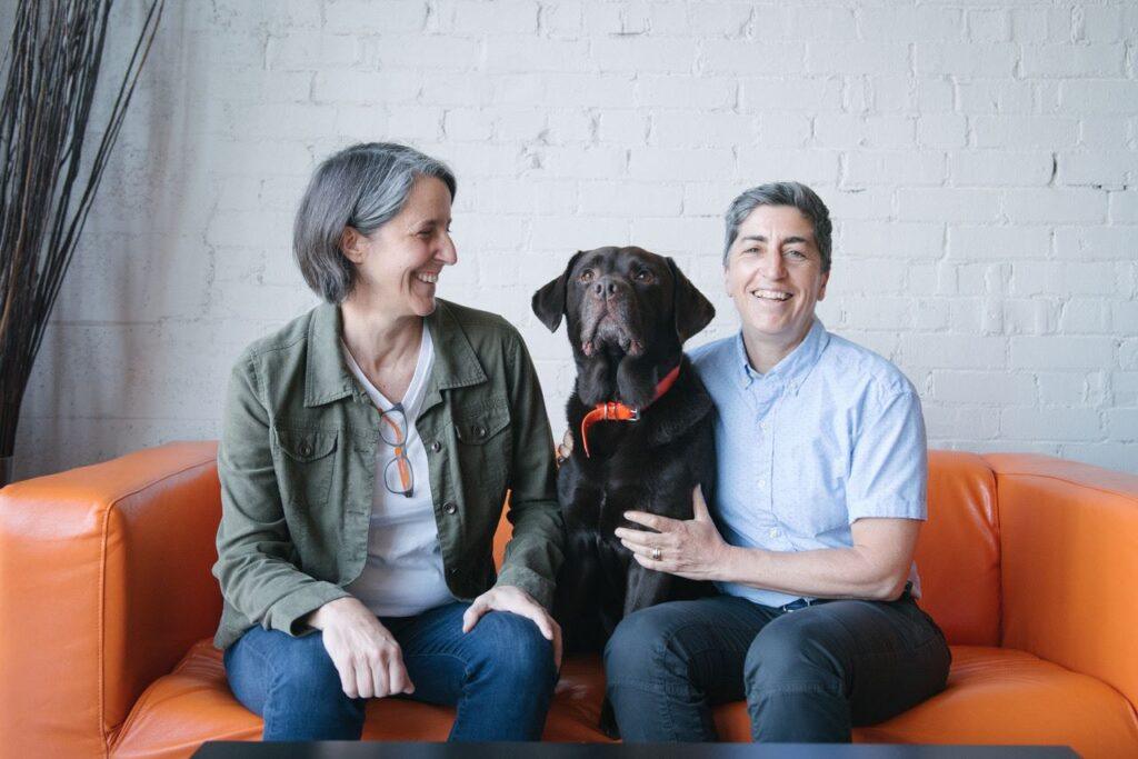 denise and sarah on the orange couch with a dog